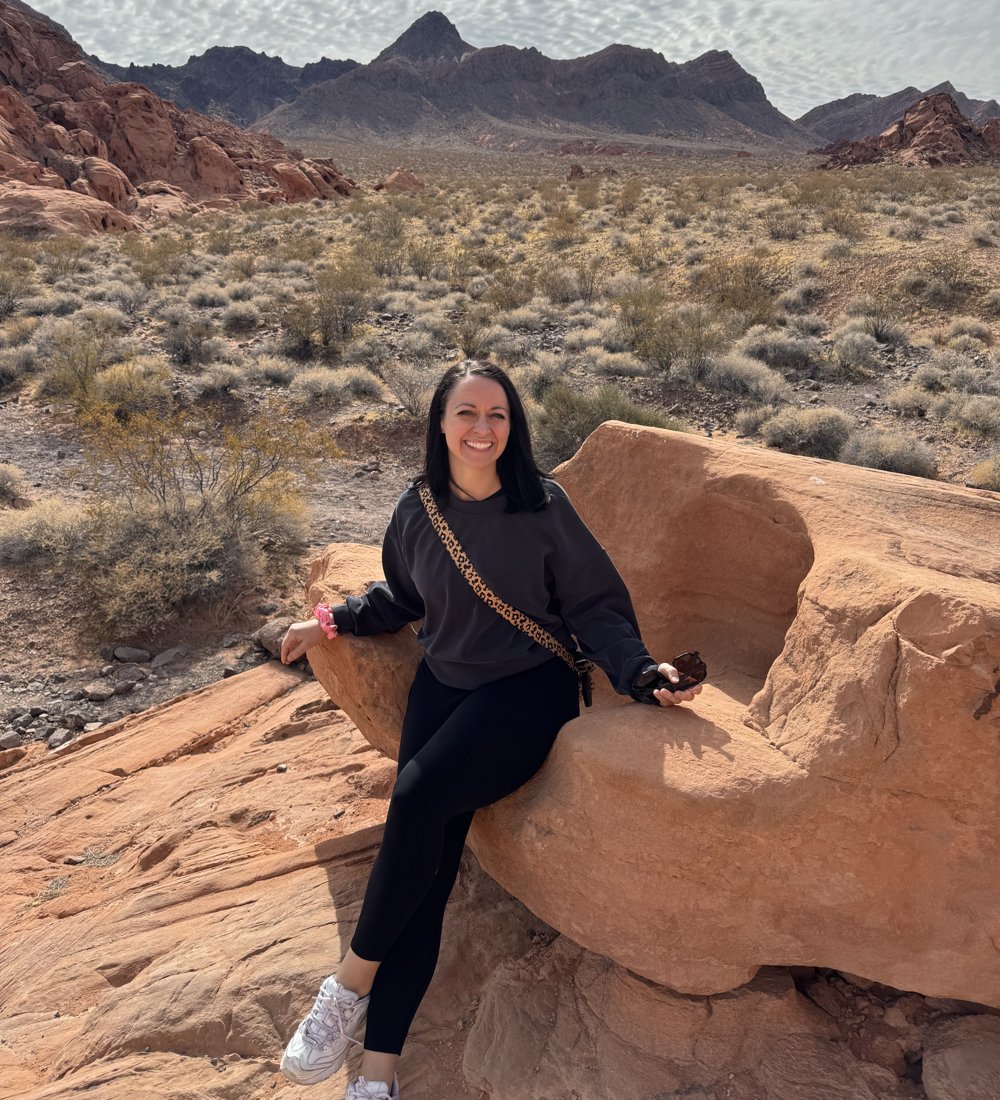 Amanda sitting on red rocks in the desert