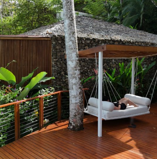 A hanging daybed cabana on a wooden deck