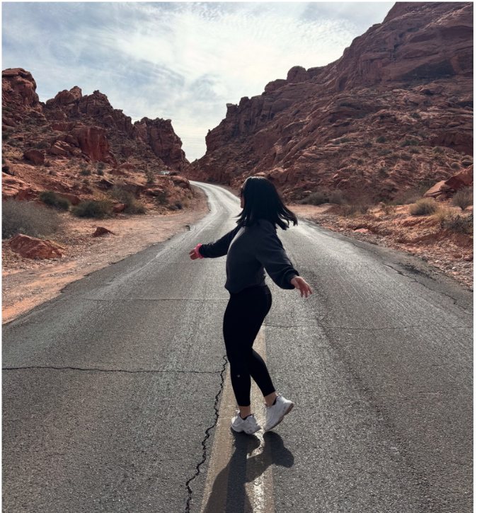 Amanda walking down an empty desert road between red rock canyons