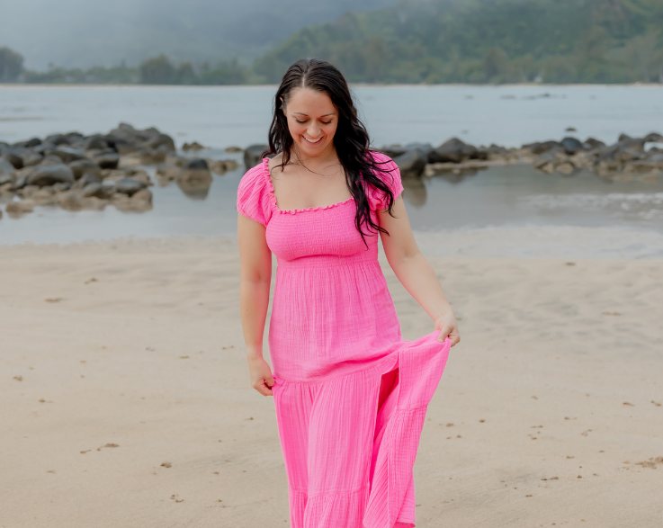 Amanda walking along the shoreline in a pink dress