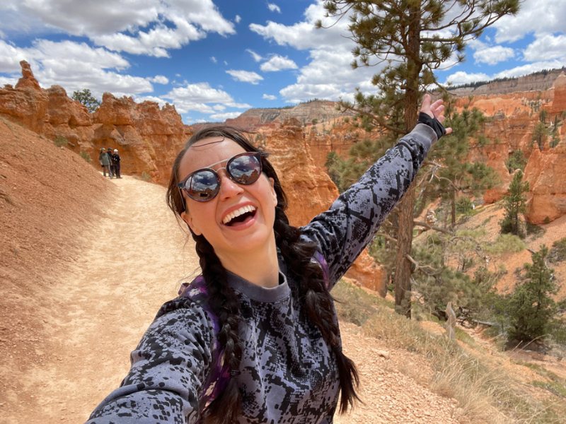 Amanda smiling in sunglasses with red rock canyons behind her